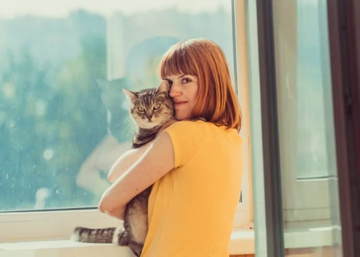 lady hugging her cat near the window