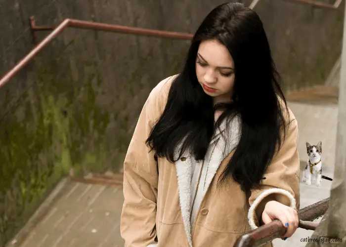 girl on the stairs being followed by a small cat