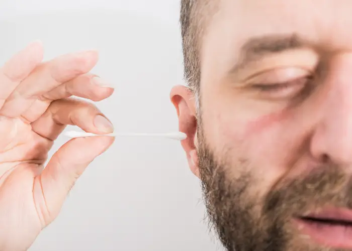 man using a q tip in his right ear