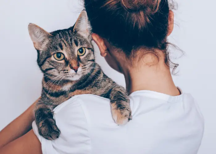 a lady in white shirt carrying her cat